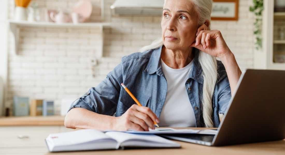 Older woman with laptop thinking.